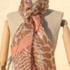 A very soft an elegant shawl in beige color with pink details.