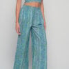 Woman wearing green boho wide-leg trousers with floral botanical print, elastic waistband, and relaxed summer fit.
