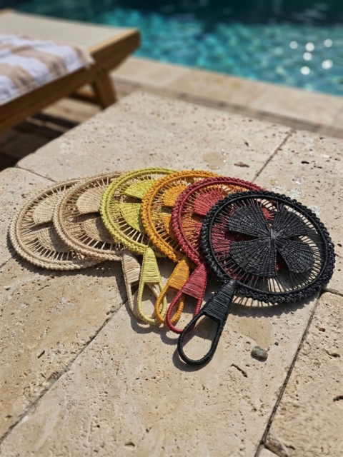 Handmade colorful Colombian palm leaf fans arranged beside a swimming pool.