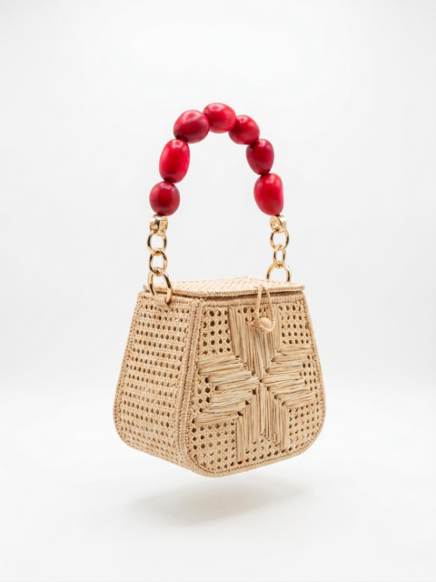 Handmade Colombian palm leaf bag with woven design and green tagua seed handle on white background.